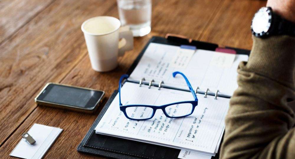 Open planner and reading glasses on a desk